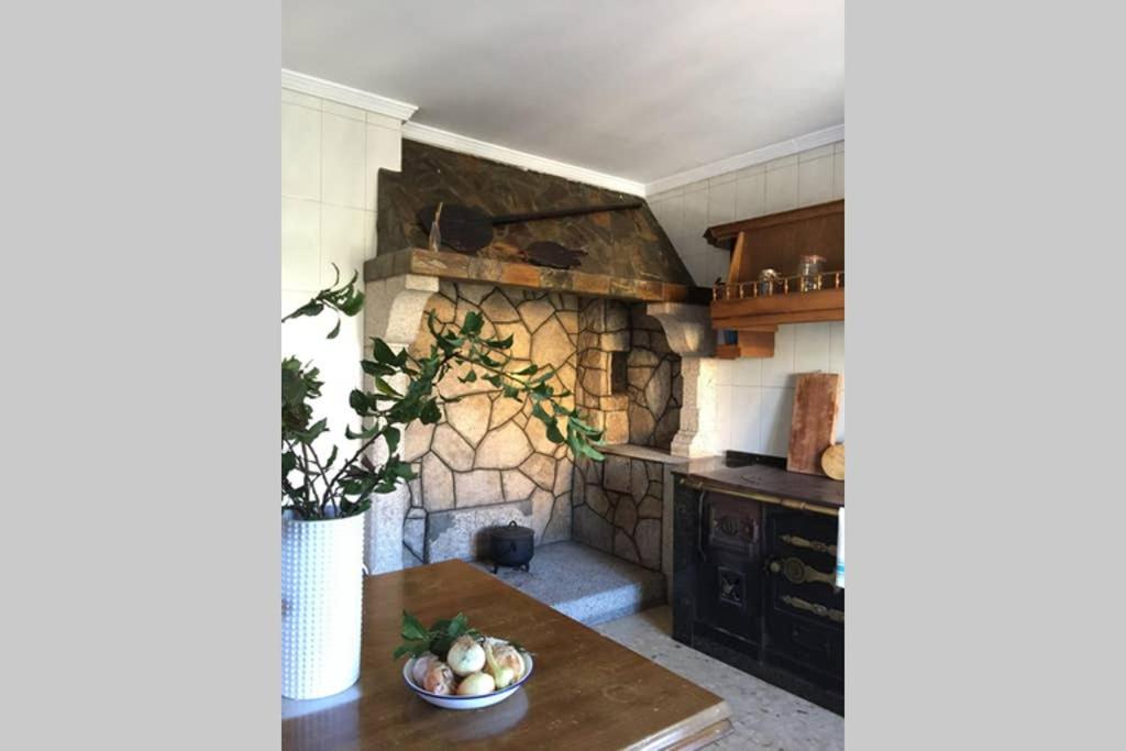 a kitchen with a table and a stone fireplace at Casa Rural Picape in Pedre