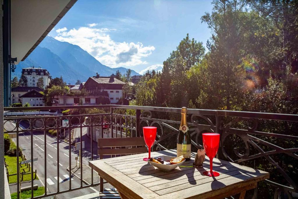 un tavolo in legno con 2 bicchieri da vino sul balcone di Le Paradis 15 Apartment - Chamonix All Year a Chamonix-Mont-Blanc