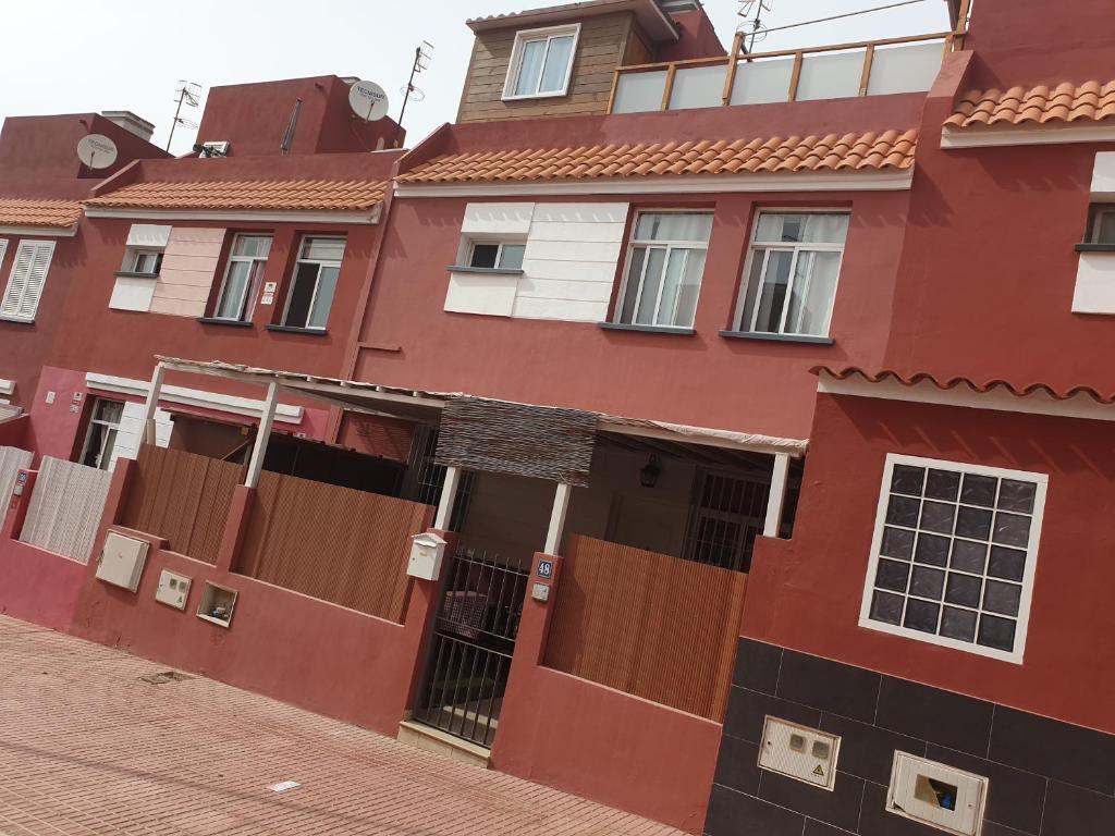 a red building with brown doors on a street at Kiki vivienda Bed & breakfast in San Isidro