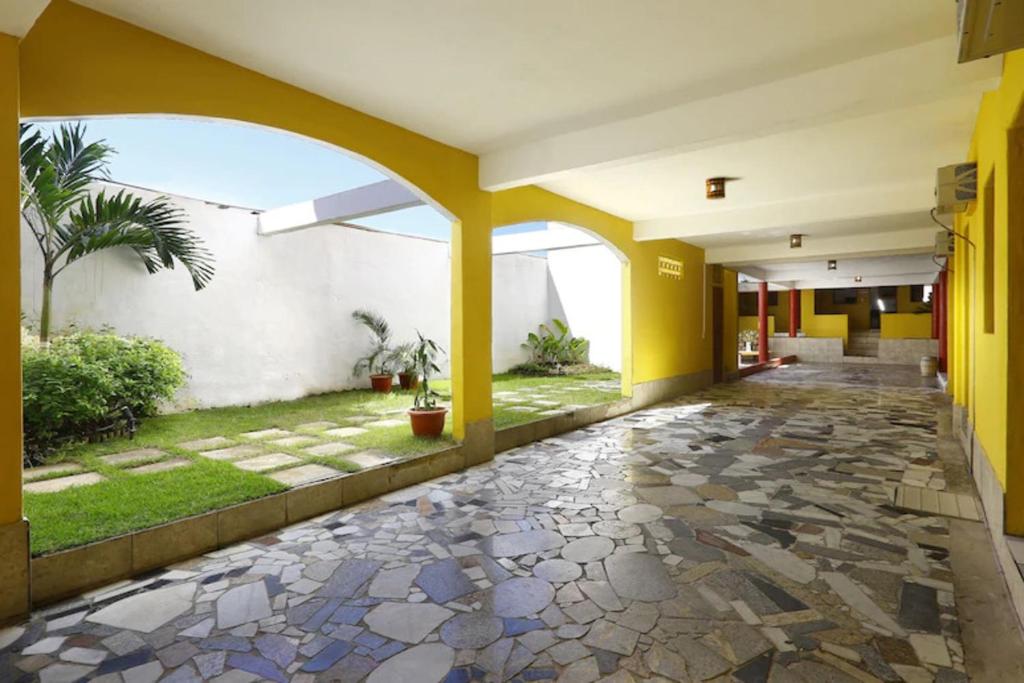 an empty hallway of a building with yellow columns and a courtyard at Capital O Recanto Da Vila Hotel, Porto Seguro in Trancoso