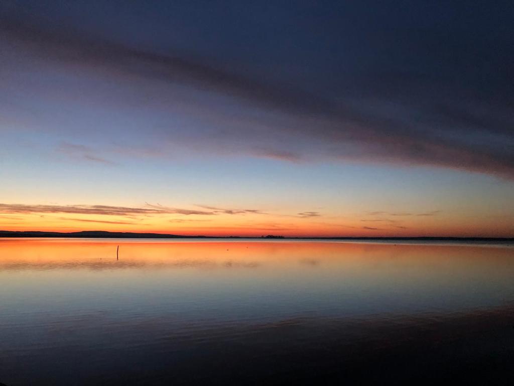 a large body of water with a sunset in the background at Ferienwohnung Storchennest - Erholung für Naturliebhaber in Auhagen