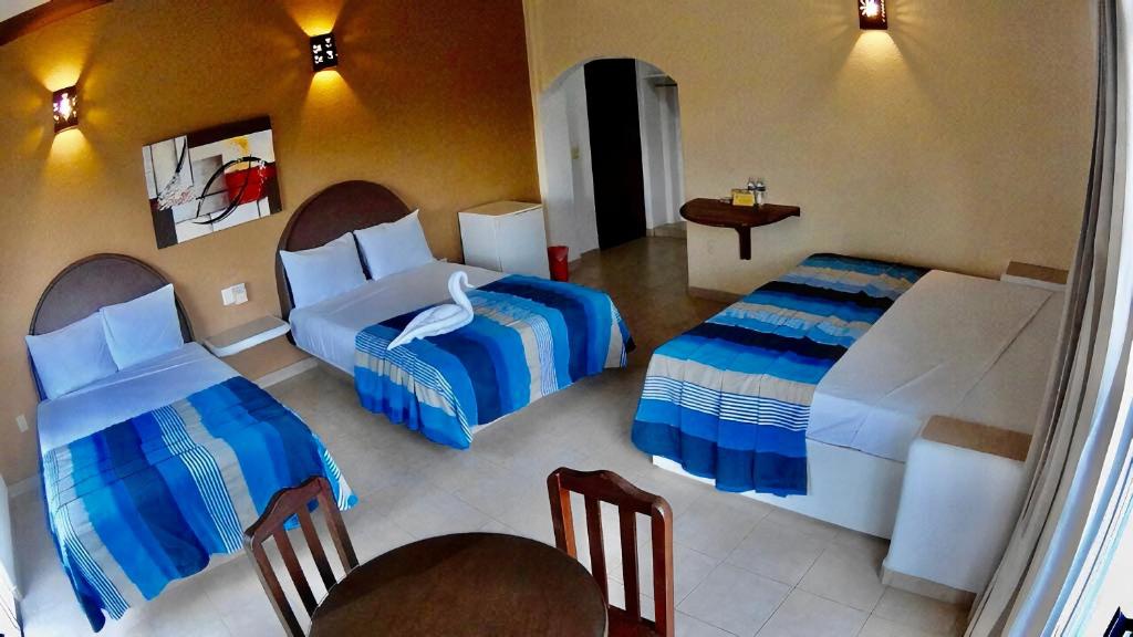 1 dormitorio con 2 camas, mesa y sillas en Hotel Bahia Huatulco, en Santa Cruz Huatulco