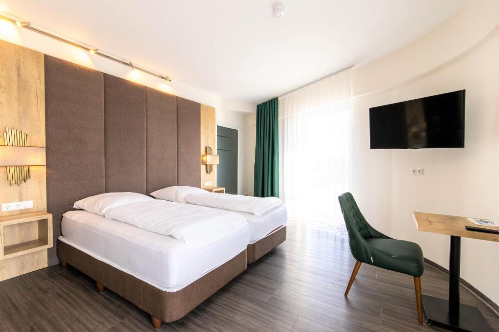 a bedroom with a bed and a desk and a chair at Luxstay Karben Neue Mitte - Self-Check-In in Karben