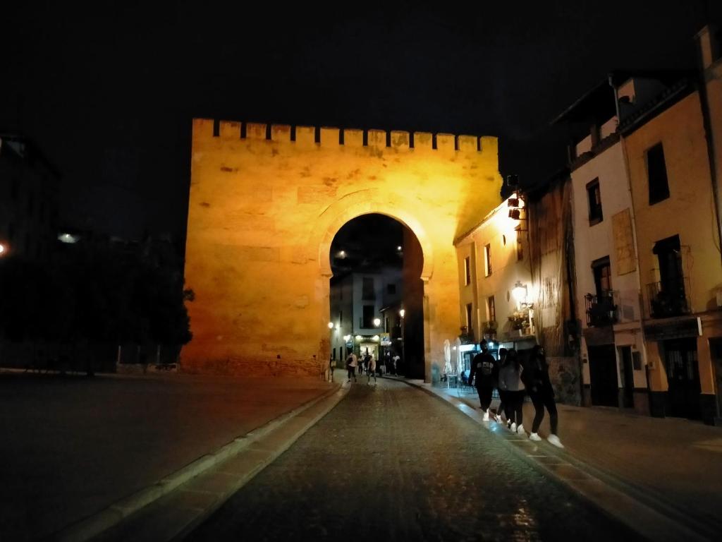 Un arco en un castillo de noche con gente caminando por una calle en MAJESTUOSA ALHAMBRA Nuevo apartamento, en Granada