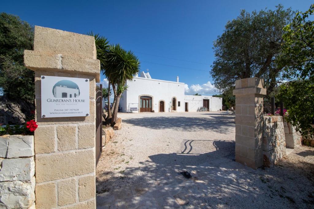 a white building with a sign in front of it at Guardian's House in Monopoli