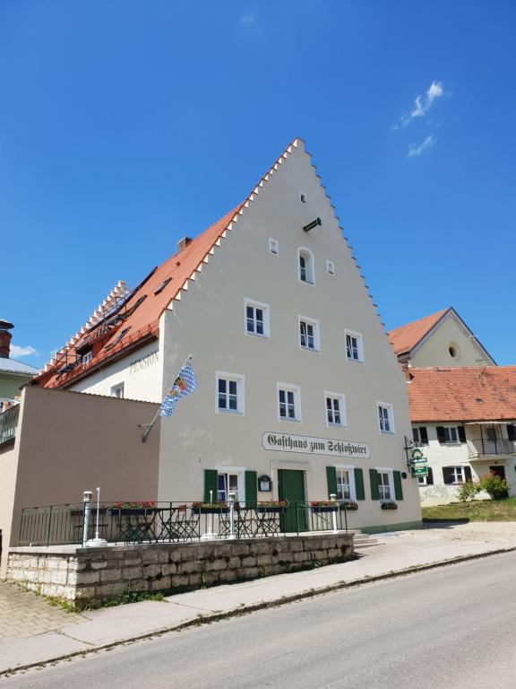 een groot wit gebouw aan de straatkant bij Gasthaus zum Schloßwirt in Dietfurt