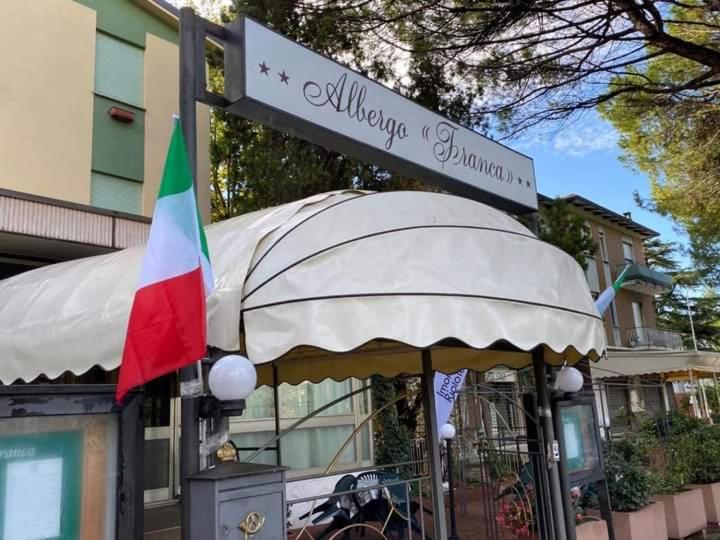 un panneau indiquant un restaurant avec drapeau et un bâtiment dans l'établissement Hotel Franca, à Riolo Terme