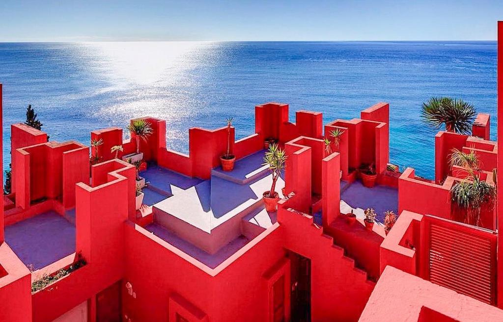 un edificio rojo con el océano en el fondo en Apartamento Muralla Roja 0507, en Calpe