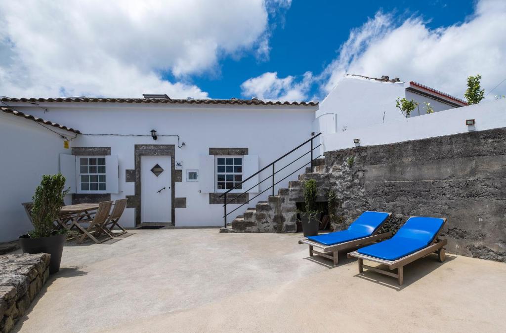 a patio with two blue lounge chairs in front of a white house at Casa Vista da Marquesa in Nordeste