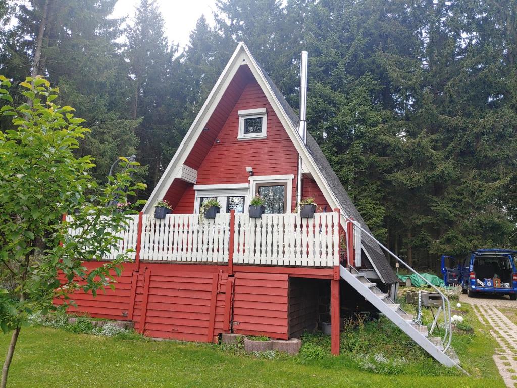 a red house with a porch and a white fence at Wanderhütte Zum Glückstal in Neuhaus am Rennweg