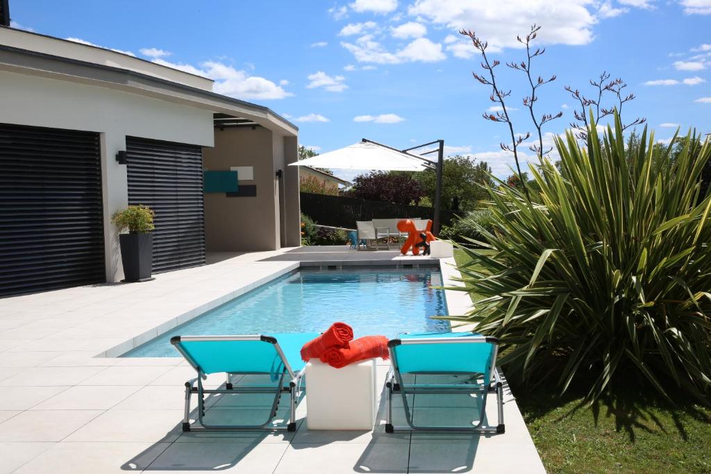 una piscina con 2 sillas y un cangrejo rojo en el medio en Maison Cube, en Saint-Didier-au-Mont-dʼOr