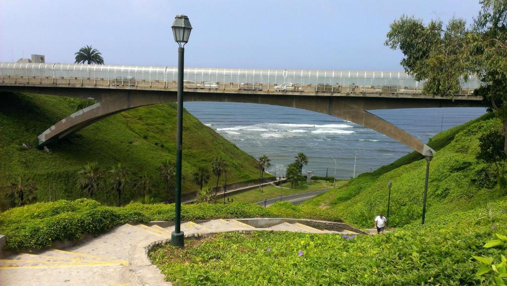 a bridge over the ocean with a person walking under it at Terrazas Apartments Miraflores in Lima