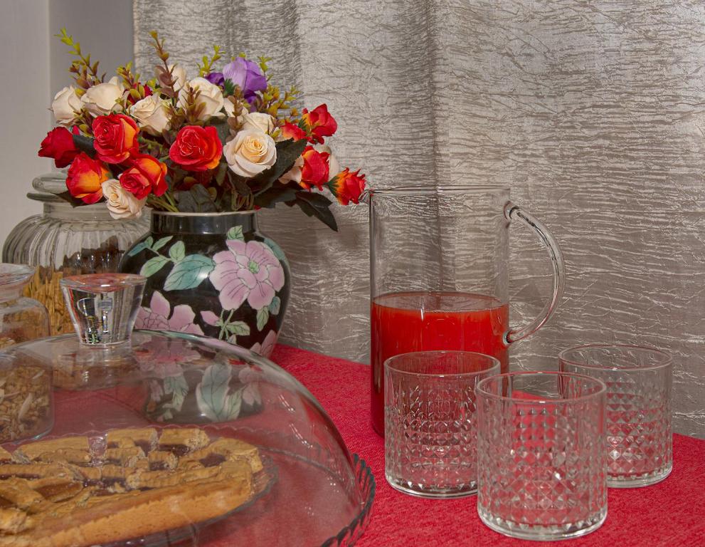 a table with a vase of flowers and a drink at B&B Dei Cavalieri in Pisa