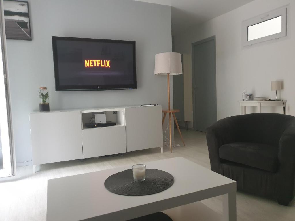 sala de estar con TV, silla y mesa en L èphéjules en Marseillan