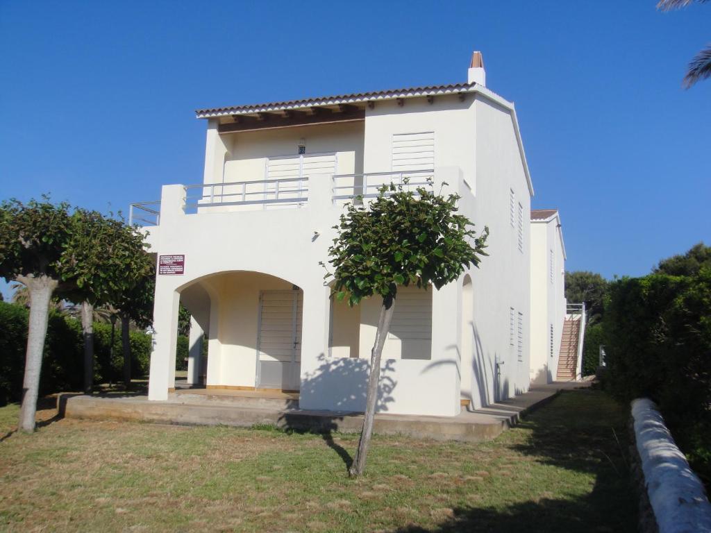 a white house with a tree in front of it at Apartamentos Rayma I-II-III in Cala Blanca
