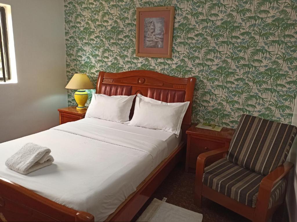 a bedroom with a bed and a chair in it at Hotel Saint-Jean in Cotonou