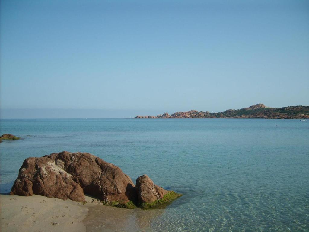 een strand met een grote rots in het water bij I Villini di Baia Delle Mimose in Badesi
