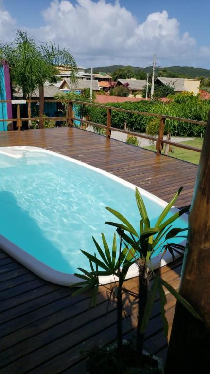 a blue swimming pool on a wooden deck with a plant at Hindu Box Containers e Cabanas in Praia do Rosa
