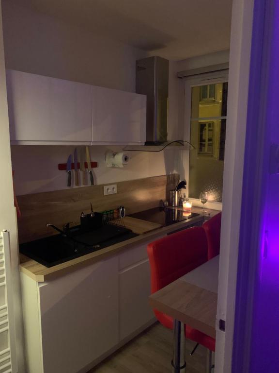 a kitchen with white cabinets and a sink and a table at Rare ! Appartement Tout Confort Plein Centre Ville in Rennes