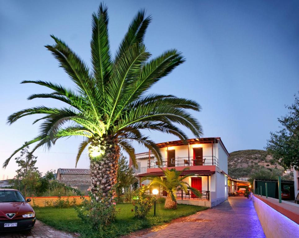 a palm tree in front of a house at Andriotis Studios in Skála Loutrón