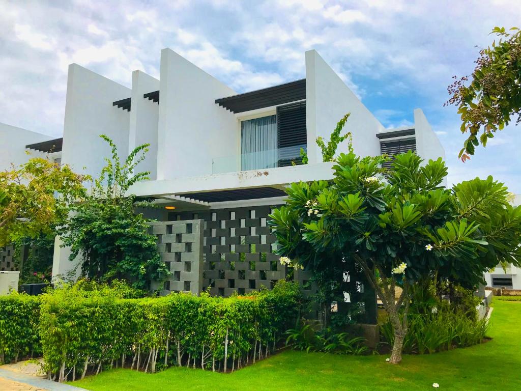 una casa blanca con árboles delante de ella en Oceanami 3BR Villa - Vivian Homestay, en Long Hai