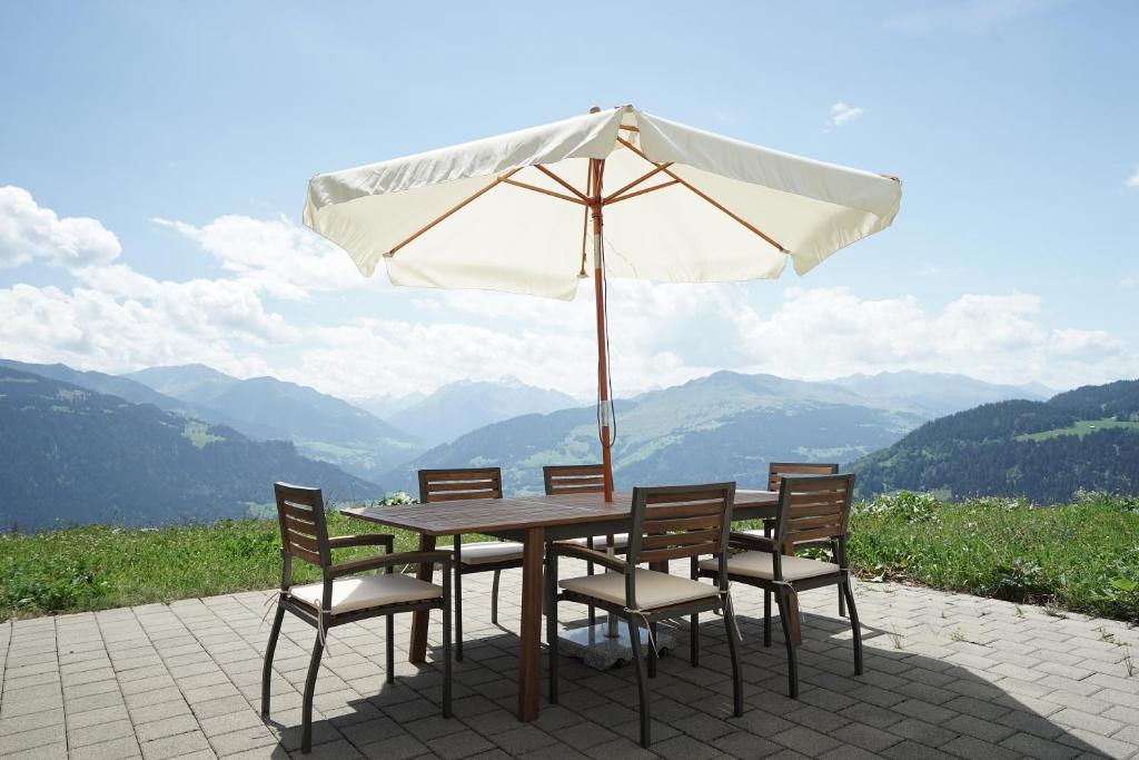 einen Holztisch mit Stühlen und einem Sonnenschirm in der Unterkunft Clasgieri - 3-Zimmer-Ferienwohnung für 4 - 6 Personen, 65m2 in Falera