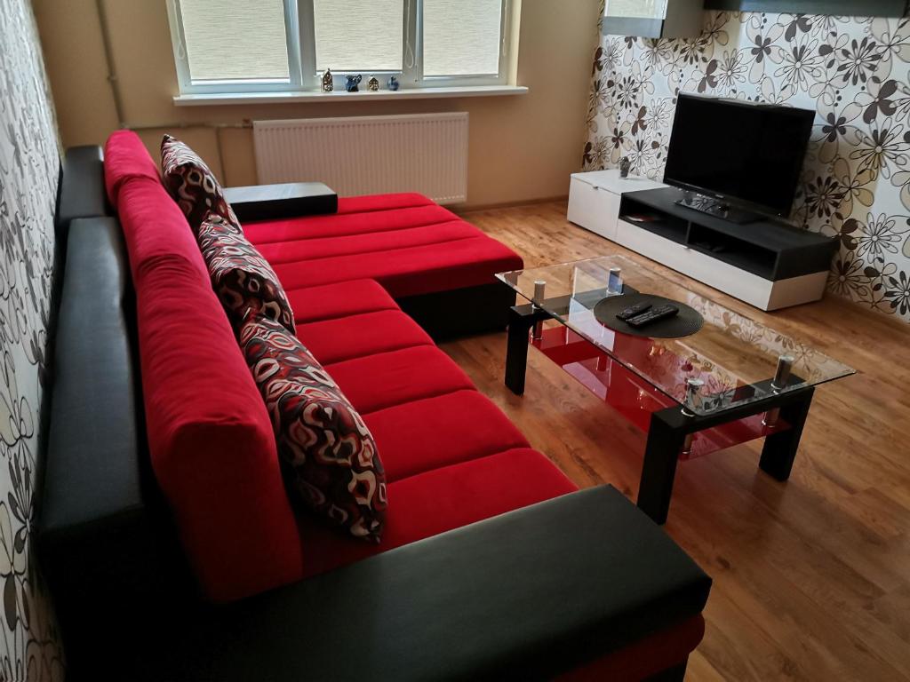 a living room with a red couch and a television at Sunny apartment Kėdainiai in Kėdainiai