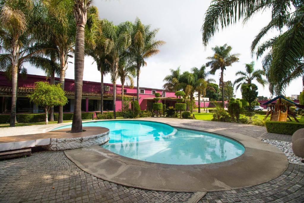 uma piscina com palmeiras em frente a um edifício em Collection O Las Iglesias, Cholula em Cholula