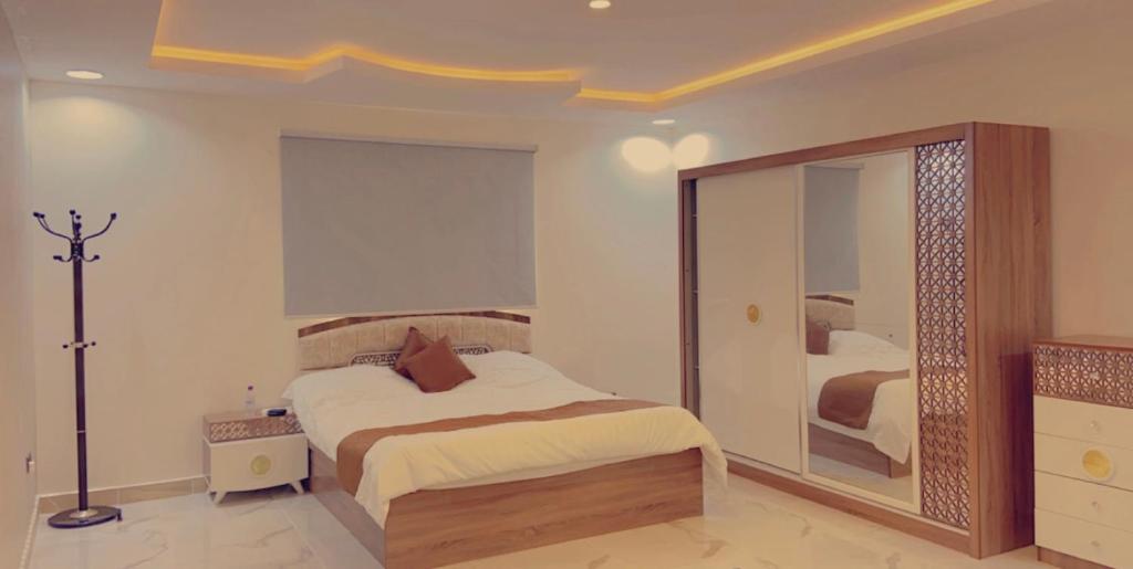 - une chambre avec un lit et un grand miroir dans l'établissement شاليهات لودج, à Al Humaizah