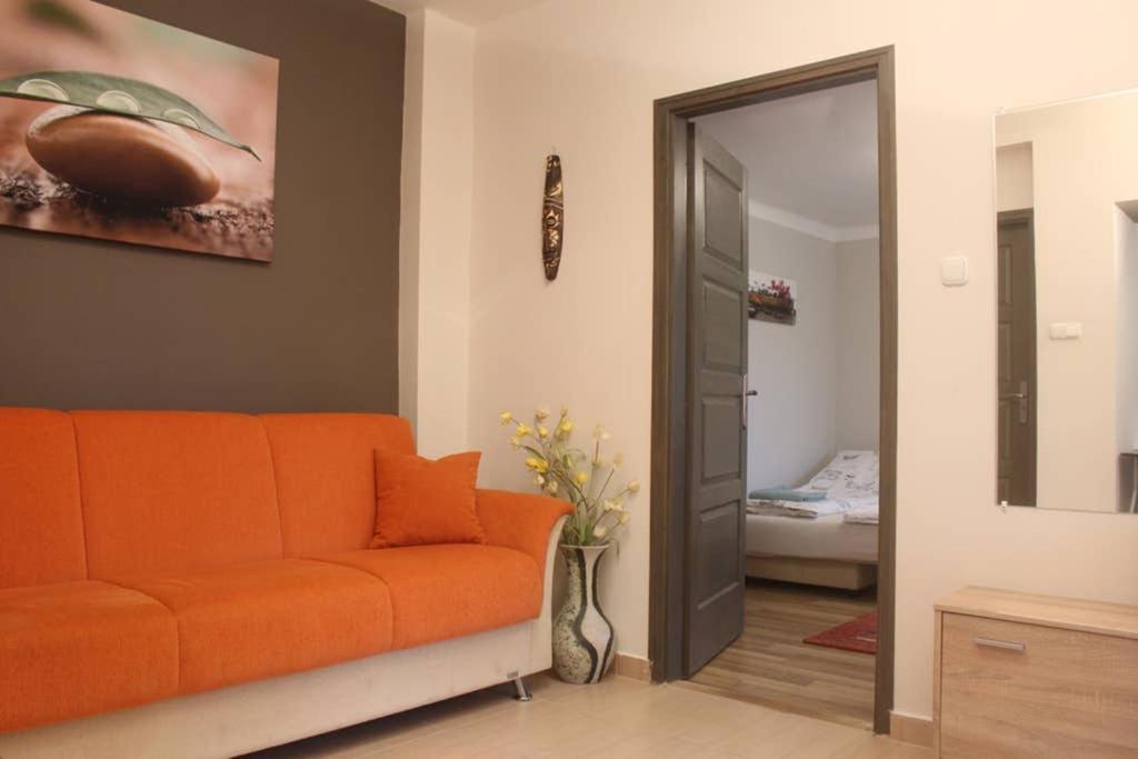 a living room with an orange couch and a bedroom at Green garden apartment in Szeged