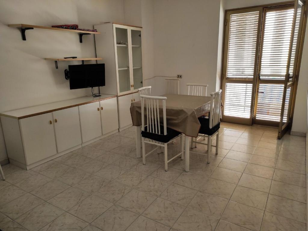 une salle à manger avec une table, des chaises et une télévision dans l'établissement Appartamento a pochi passi dal mare, à Villapiana