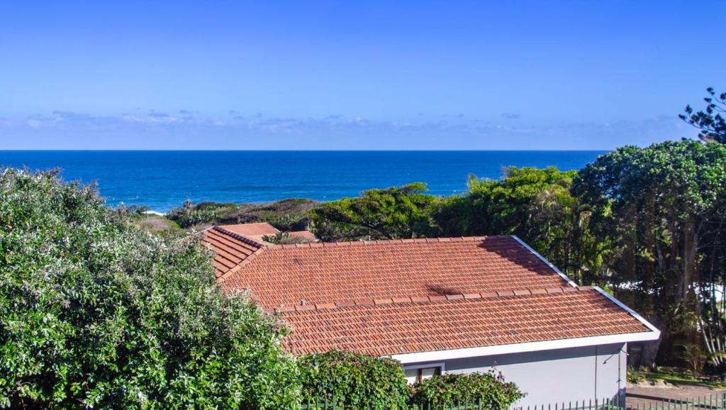 una casa blanca con techo rojo y el océano en 15 @ Porter Guesthouse, en Port Shepstone