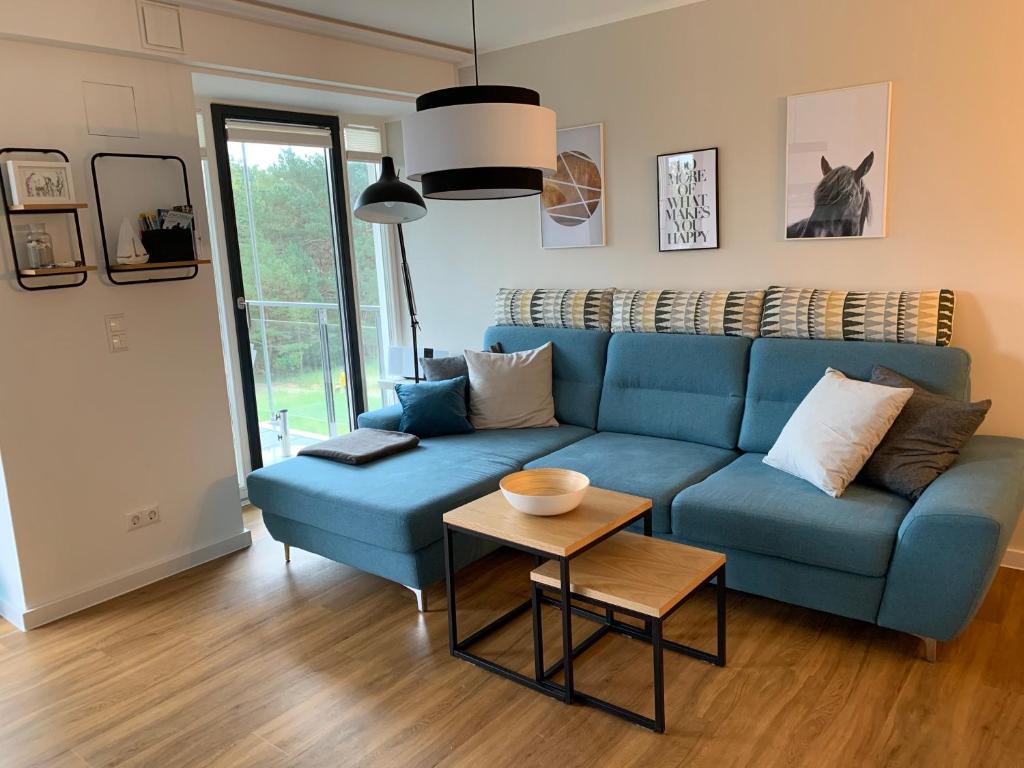 salon z niebieską kanapą i stołem w obiekcie Heimathafen Prora, 3.OG mit Meerblick w mieście Binz