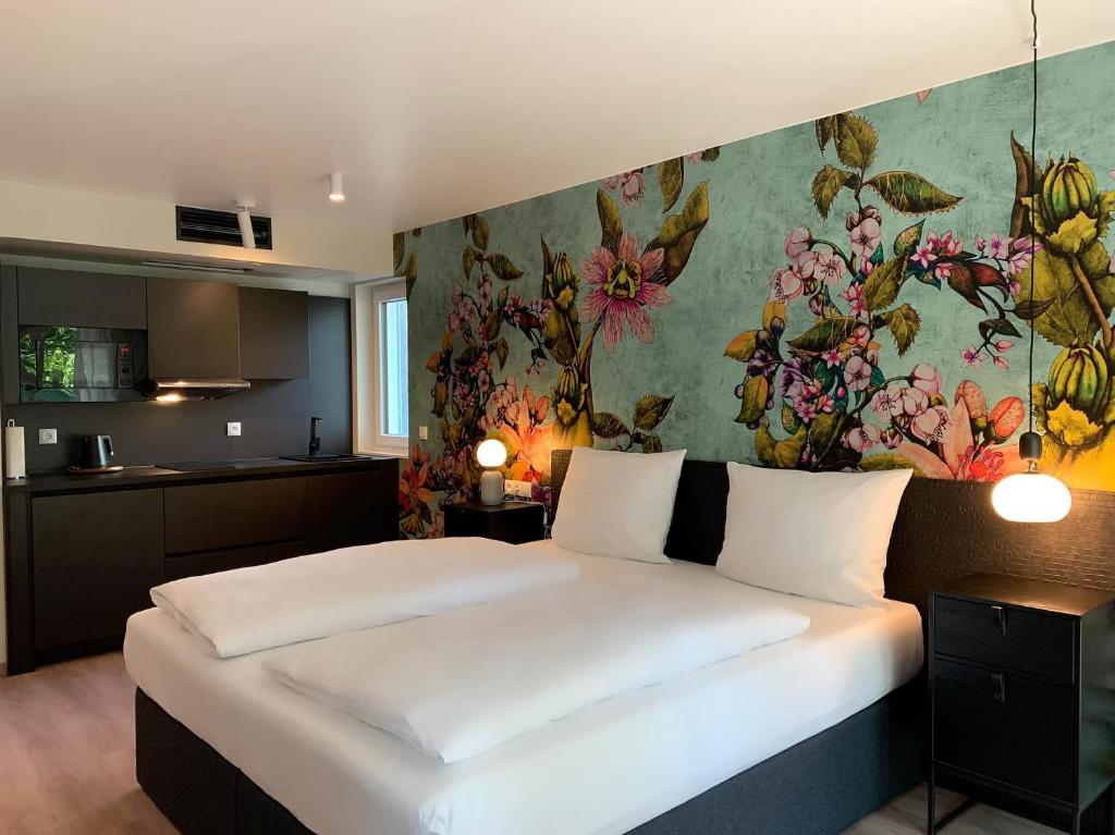 a bedroom with a large bed with a floral wall at ANA Living Karlsruhe by Arthotel ANA in Karlsruhe