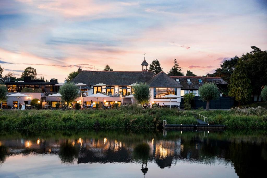 uitzicht op een hotel vanaf het water bij zonsondergang bij Mooirivier in Dalfsen