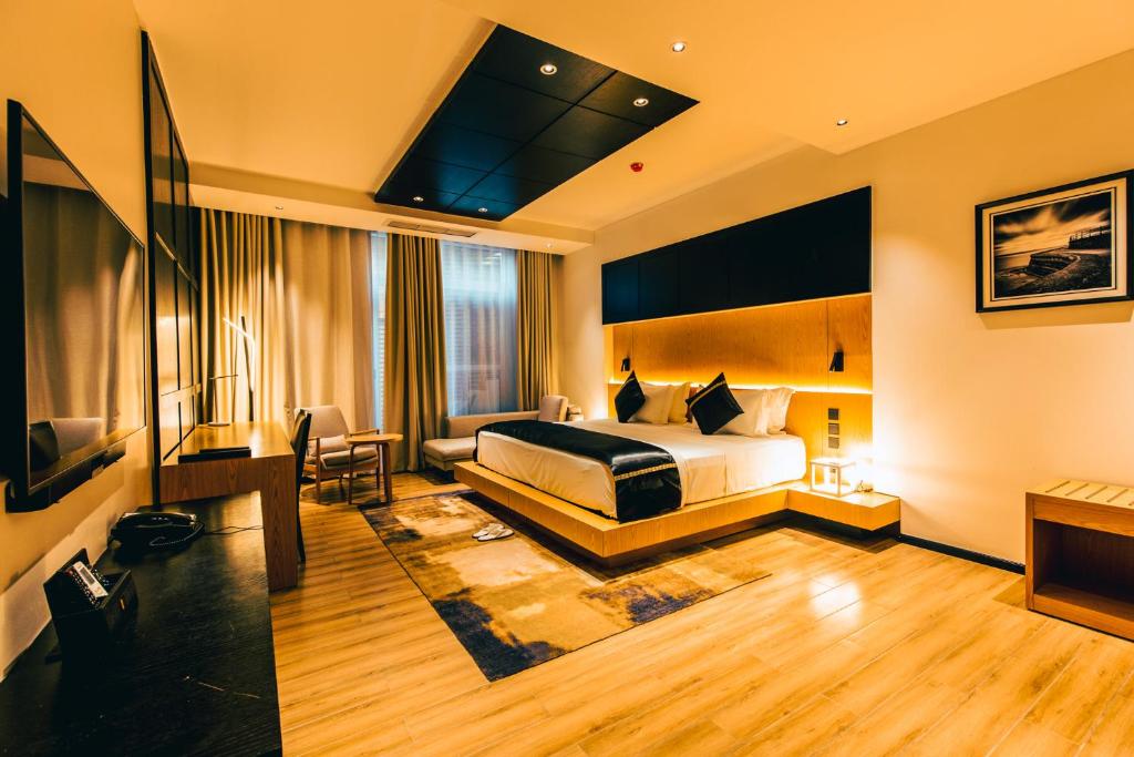 um quarto de hotel com uma cama e uma televisão em Blackwood Boutique Hotel and Apartments em Dar es Salaam