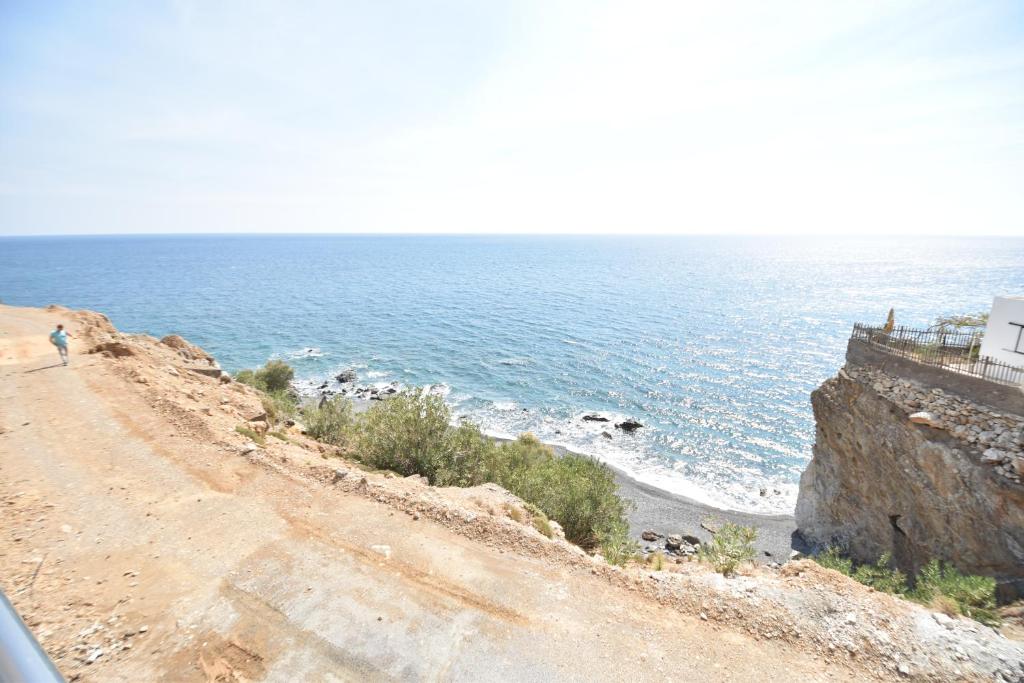a person walking down a dirt road next to the ocean at House With View in Paránimfoi