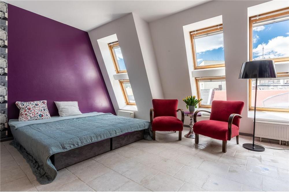 1 dormitorio con 1 cama y 2 sillas rojas en Apartament Broadway, en Poznan
