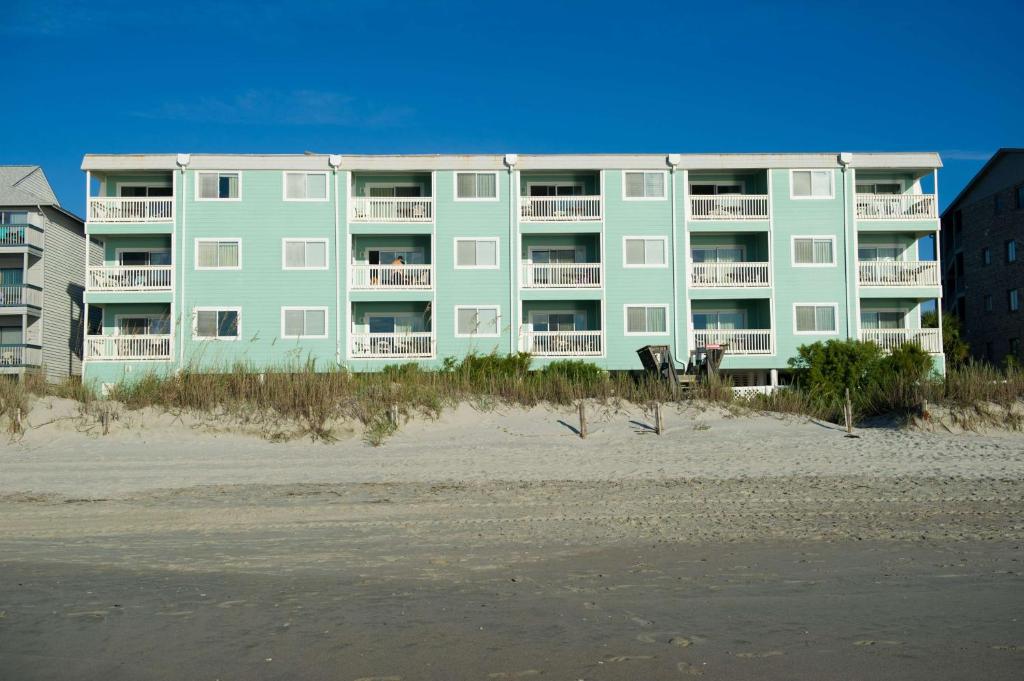 a large apartment building on the beach next to the beach at Sandpebble Beach Club Surfside Beach a Ramada by Wyndham in Myrtle Beach