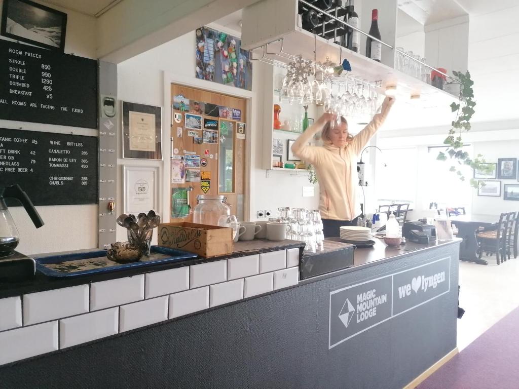 a man standing behind the counter of a restaurant at Magic Mountain Lodge - Lyngen in Lyngseidet