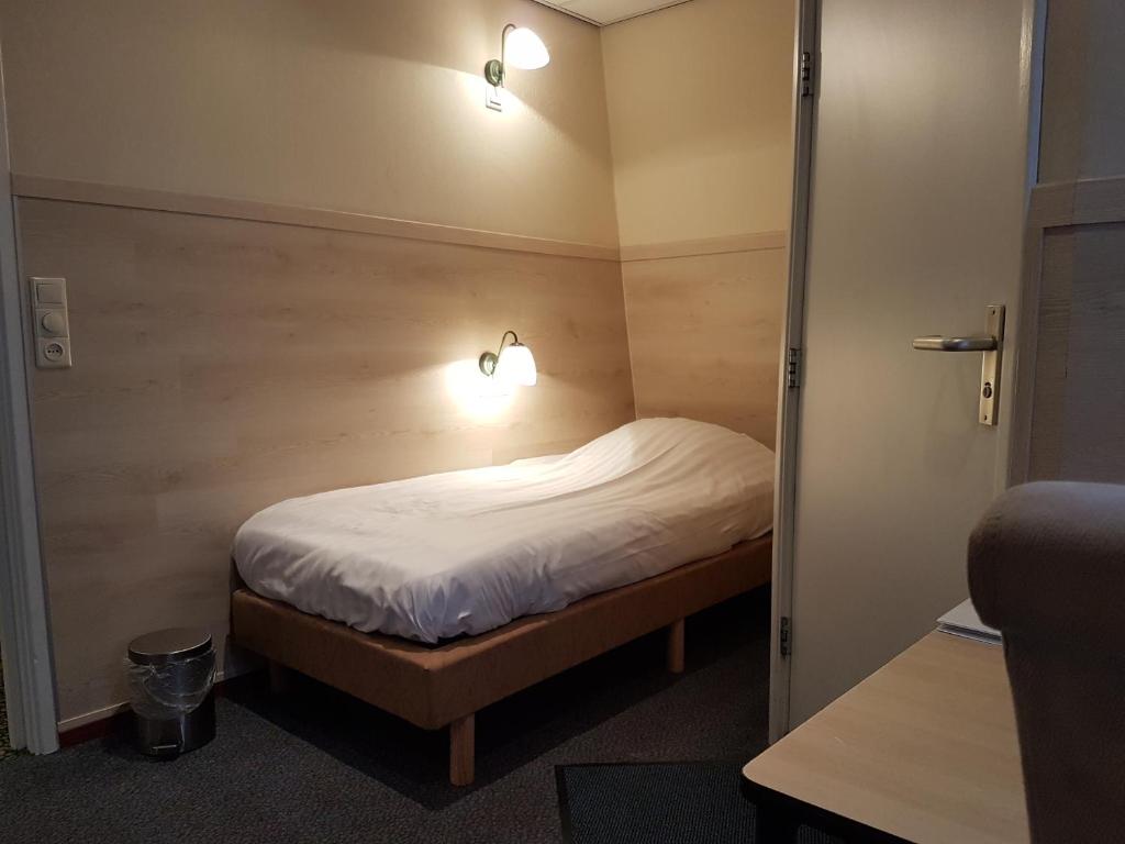 1 dormitorio pequeño con 1 cama con 2 luces. en Hotel Het Galjoen, en Dronten