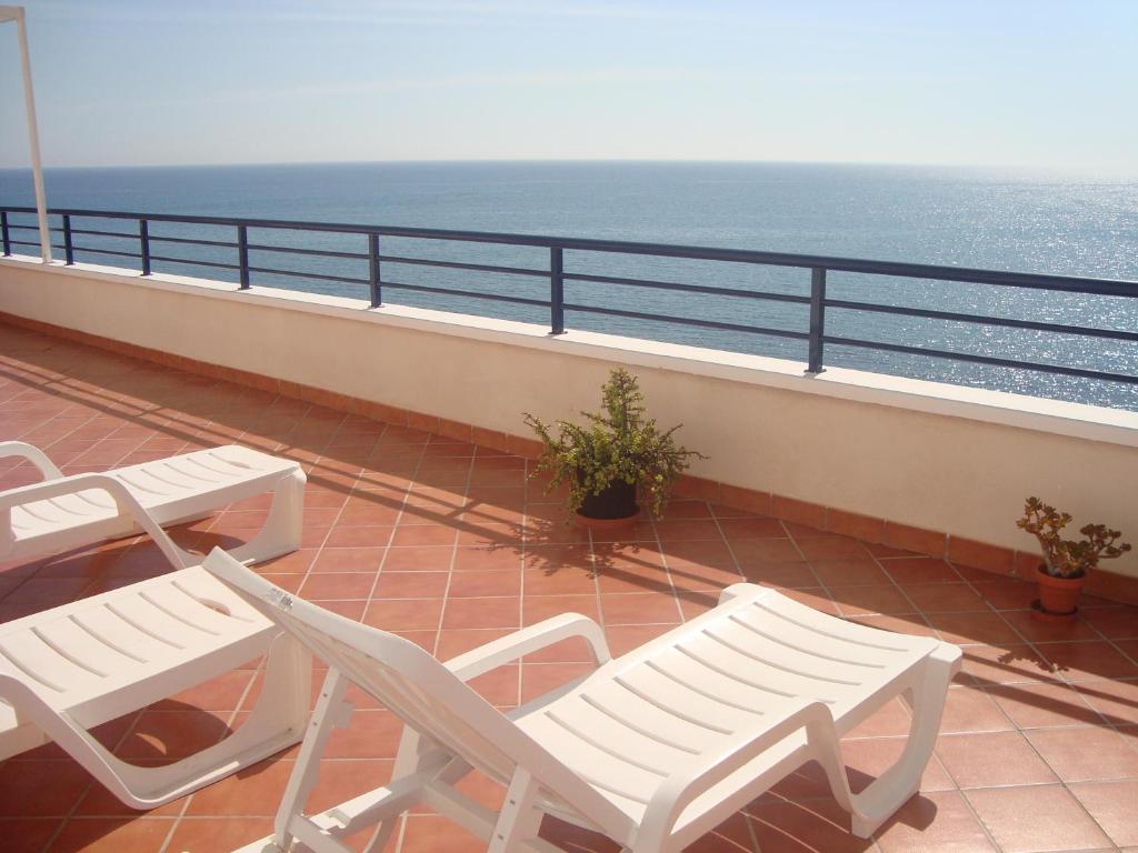 a balcony with two white chairs and the ocean at Apartamentos Sotavento Carboneras in Carboneras