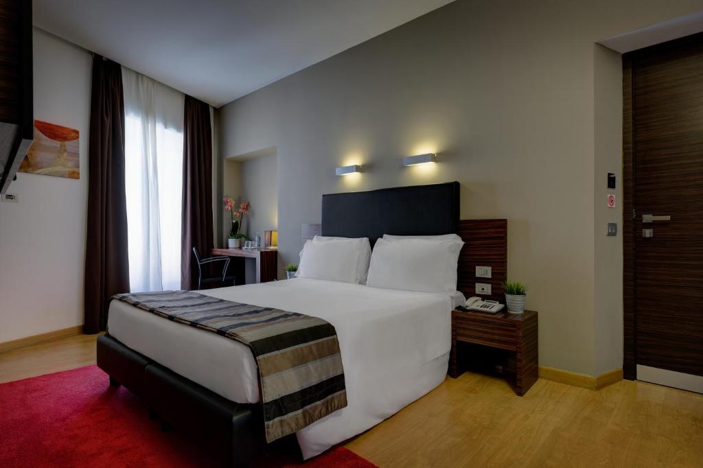 Un dormitorio con una gran cama blanca y una mesa en Trevi Collection Hotel - Gruppo Trevi Hotels, en Roma
