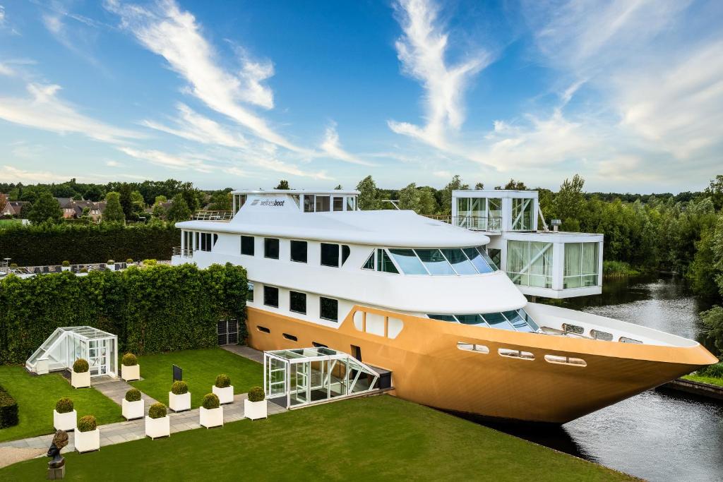 een grote boot geparkeerd op het gras naast een rivier bij Fletcher Wellness-Hotel Brabant-Mill in Mill