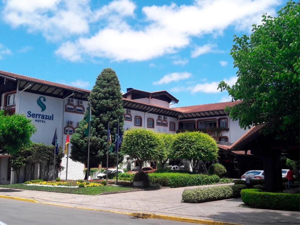 a building with a tree in front of a street at Serrazul Hotel Distributed By Intercity in Gramado