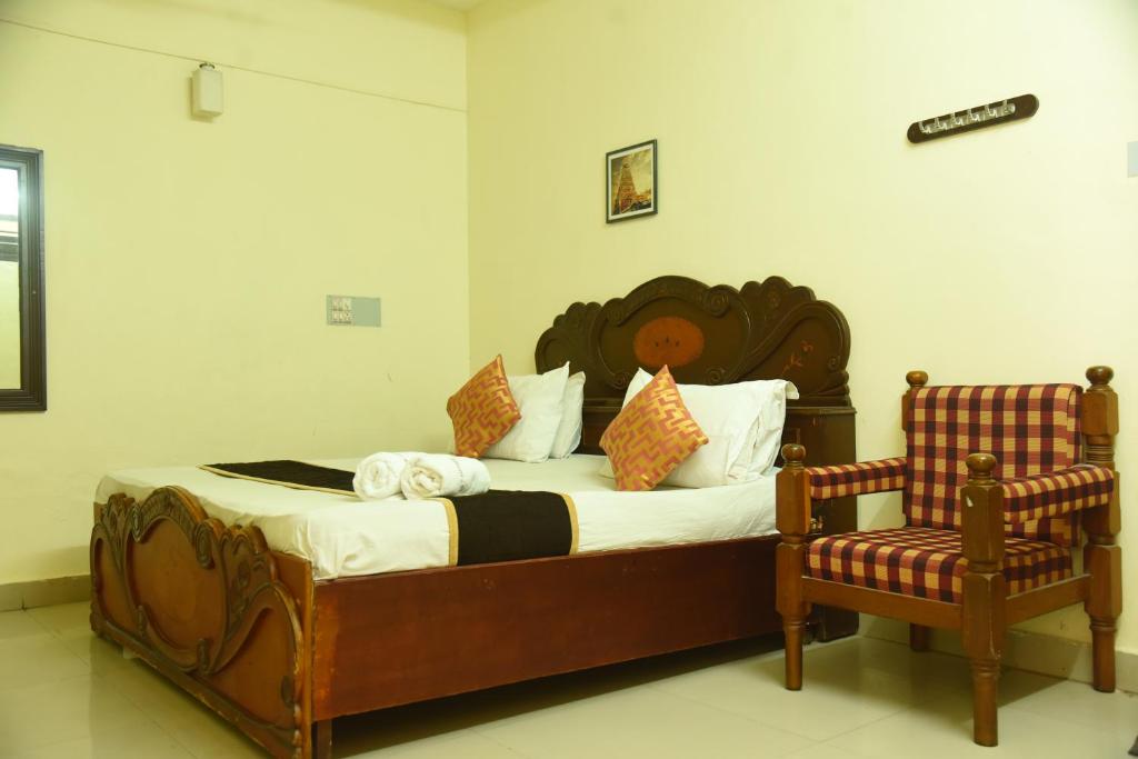 a bedroom with a large bed and a chair at Hotel Raja Palace in Kanyakumari