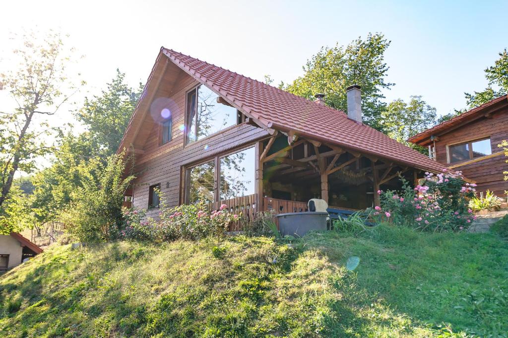 a log house with a porch and a yard at Rose Hip Hill Farm in Valea Tîrnei