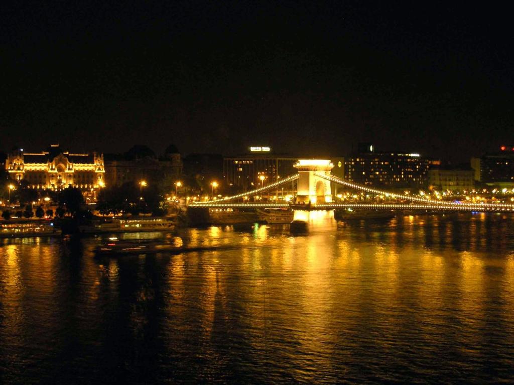a lit up bridge over the water at night at Boutique Hotel Victoria Budapest in Budapest