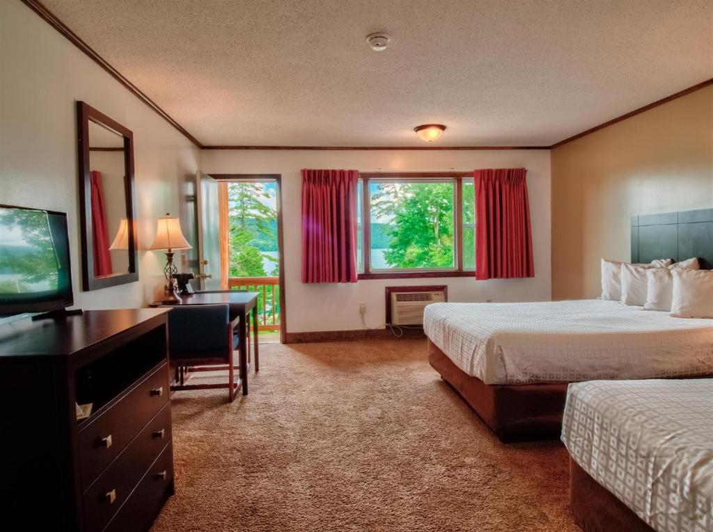 a hotel room with two beds and a desk and a television at Lake 'N Pines Motel in Cooperstown