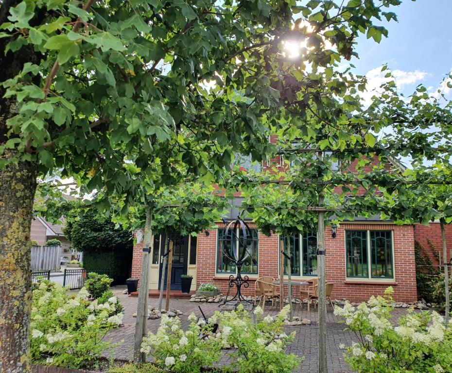 a brick house with the sun shining through the trees at B&B Die Herrlichkeit in Lage